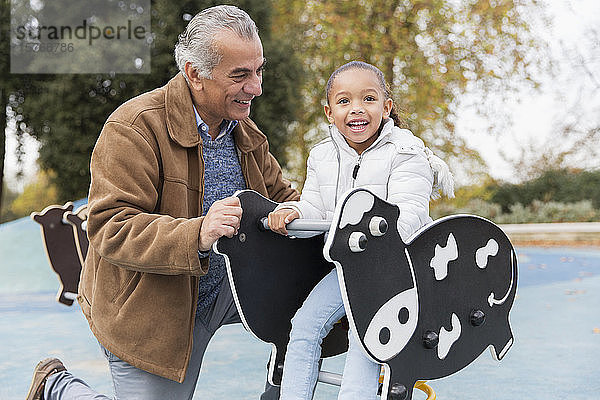 Porträt lächelnd Großvater und Enkelin spielen auf dem Spielplatz