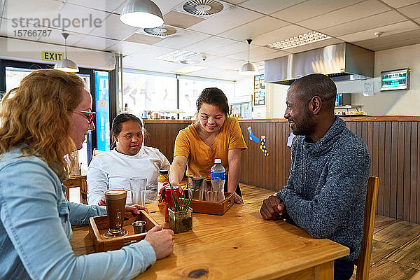 Junge Kellnerin mit Down-Syndrom serviert Getränke in einem Cafe