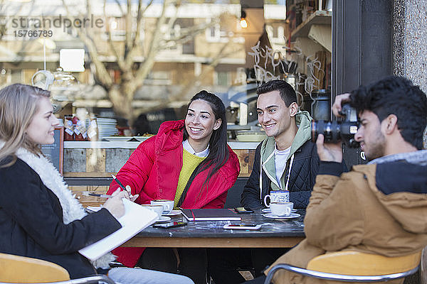 Junge Freunde hängen in einem Straßencafé ab und lernen