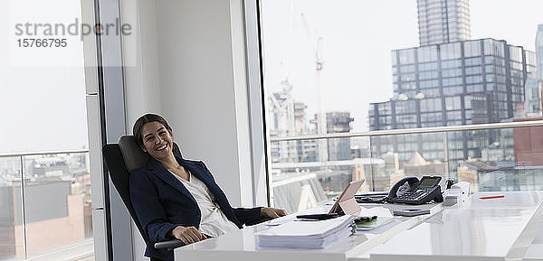 Porträt einer glücklichen  selbstbewussten Geschäftsfrau  die in einem Hochhausbüro arbeitet