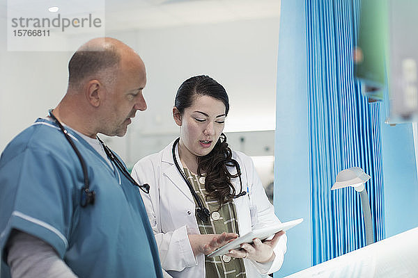 Ärzte mit digitalem Tablet im Gespräch im Krankenhauszimmer