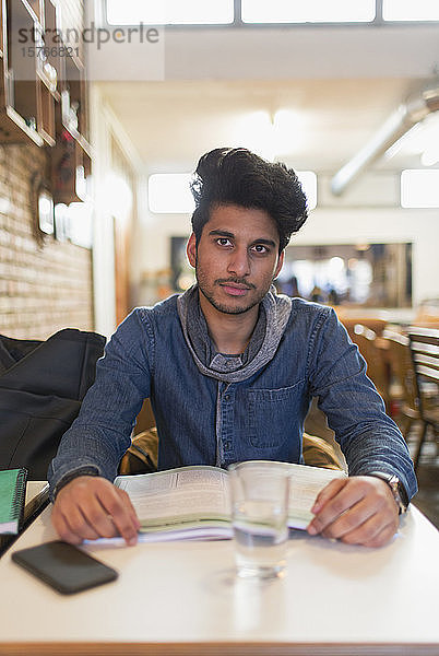 Porträt selbstbewusster junger männlicher Student  der am Cafétisch studiert