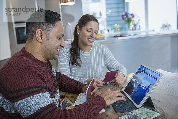 Glückliches Paar mit Pässen plant Urlaub am digitalen Tablet