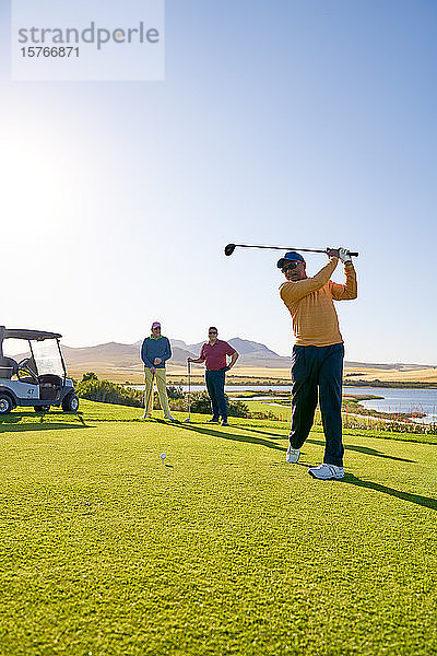 Männlicher Golfer beim Abschlag auf einem sonnigen Golfplatz