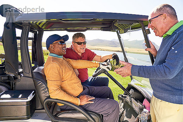 Männliche Golfer unterhalten sich am sonnigen Golfwagen