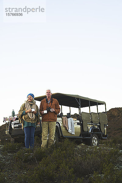 Älteres Paar auf Safari trinkt Tee außerhalb des Geländewagens