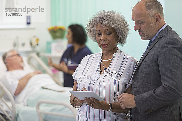 Ärzte mit digitalem Tablet bei der Visite  Beratung im Krankenhauszimmer