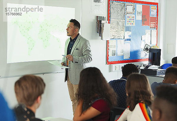 Gymnasiallehrer  der eine Geografiestunde an der Projektionsfläche im Klassenzimmer leitet