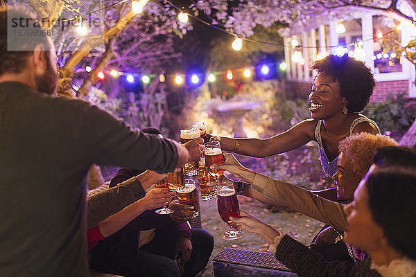 Fröhliche Freunde stoßen bei einer Gartenparty mit Biergläsern an