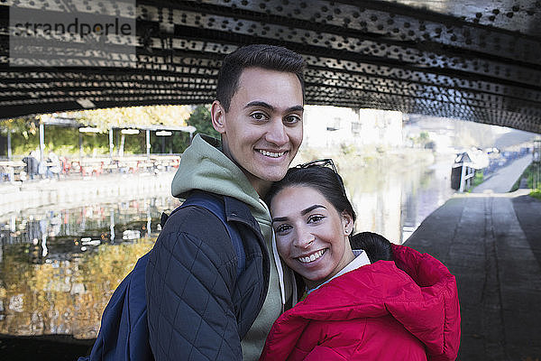 Porträt glückliches junges Paar  das sich entlang des Kanals umarmt