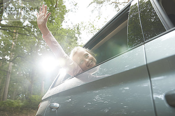 Unbekümmertes Mädchen mit Arm aus dem sonnigen Autofenster