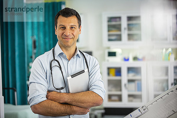Porträt selbstbewusster männlicher Arzt mit digitalem Tablet in einem Krankenhauszimmer