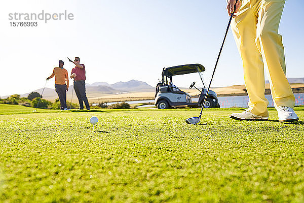 Golfer bereitet sich am sonnigen Abschlagplatz auf den Abschlag vor