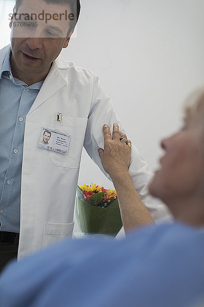 Patient berührt den Arm des Arztes im Krankenhauszimmer