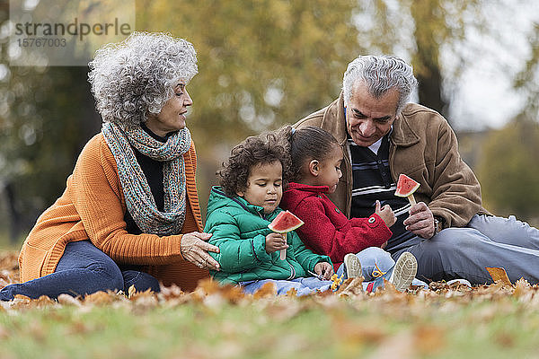 Großeltern und Enkelkinder essen Wassermelone im Herbstpark