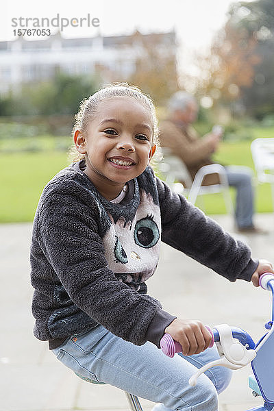 Porträt lächelndes Mädchen fährt Fahrrad auf dem Spielplatz
