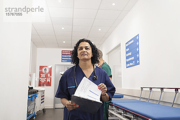 Selbstbewusste Ärztin mit Krankenblatt bei der Visite im Krankenhausflur
