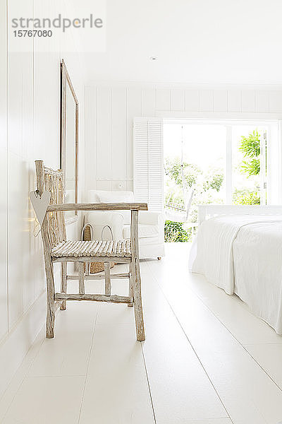 Einfacher Holzsessel im weißen Strandhaus-Schlafzimmer