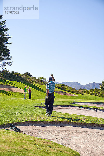 Glücklicher Mann beim Golfen  der auf einem sonnigen Golfplatz jubelt