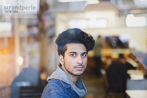 Porträt selbstbewusster junger Mann im Fenster eines Cafés