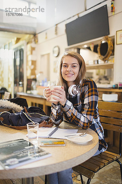 Porträt einer selbstbewussten jungen Studentin  die in einem Café Kaffee trinkt und lernt