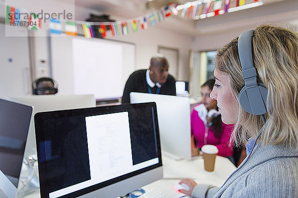 Studentin einer Volkshochschule mit Kopfhörern  die einen Computer im Computerlabor benutzt