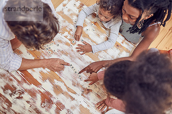 Junge Familie spielt Scrabble-Wortspiel am Tisch