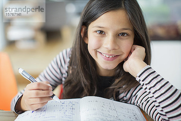 Portrait lächelndes  selbstbewusstes Mädchen bei den Hausaufgaben