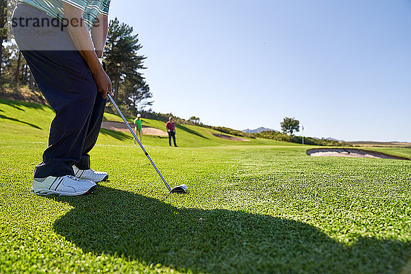 Männlicher Golfer bei einem Schlag auf dem sonnigen Golfplatz