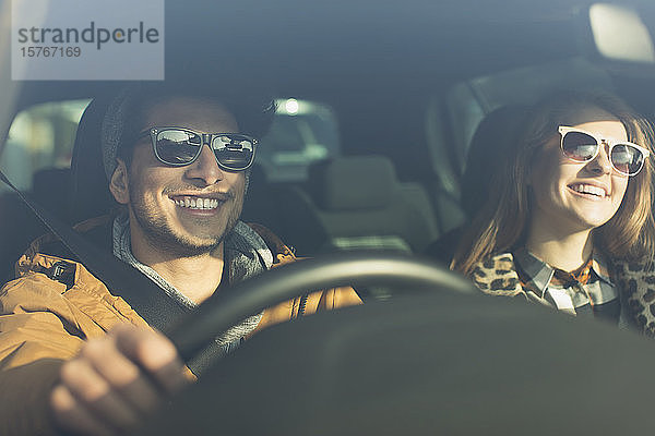 Glückliches junges Paar mit Sonnenbrille im Auto