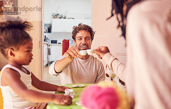 Junge Familie genießt eine imaginäre Teeparty