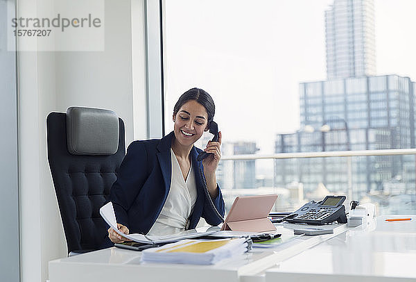 Lächelnde Geschäftsfrau im Gespräch am Telefon in einem städtischen Büro
