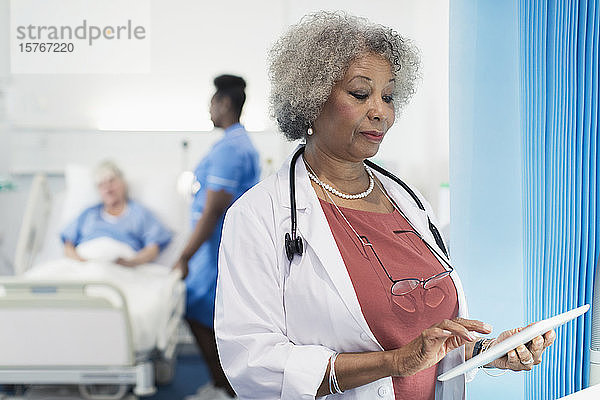 Oberärztin mit digitalem Tablet im Krankenhauszimmer