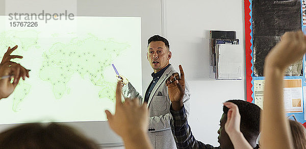 Männlicher High-School-Lehrer  der vor einer Projektionsfläche im Klassenzimmer Unterricht erteilt