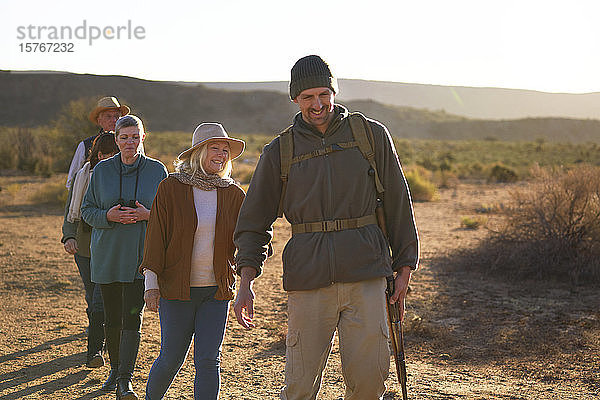 Lächelnder Safari-Reiseleiter führt Gruppe in sonnigem Grasland