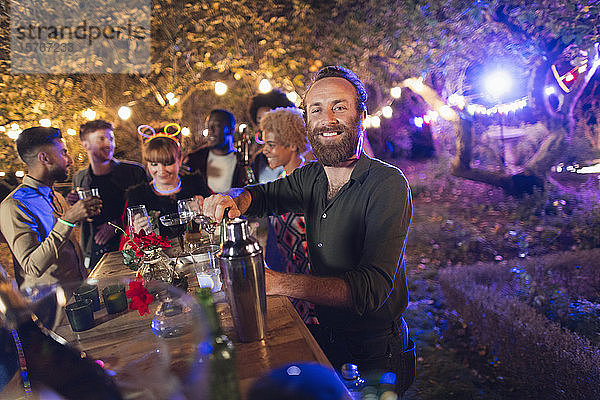 Porträt glücklicher Mann  der für Freunde bei einer Gartenparty kellnert