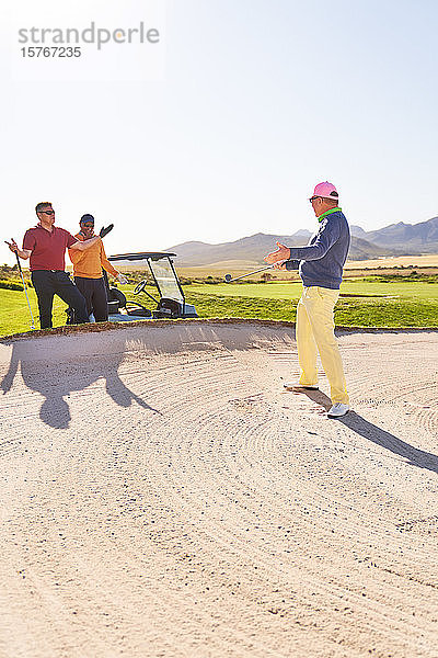 Männlicher Golfer im Bunker auf einem sonnigen Golfplatz