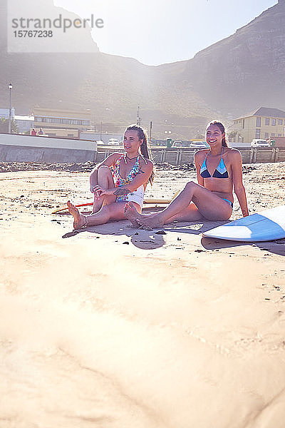 Junge Surfer-Freundinnen entspannen sich am sonnigen Strand