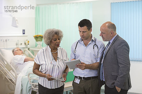Ärzte mit digitalen Tablets bei der Visite  Beratung im Krankenhauszimmer