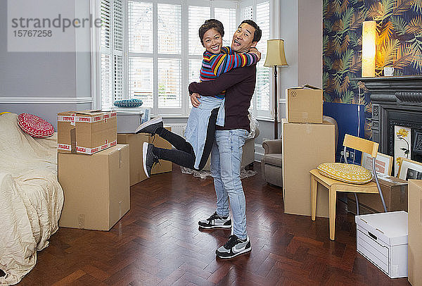 Porträt eines glücklichen  verspielten Paares beim Einzug in ein neues Haus