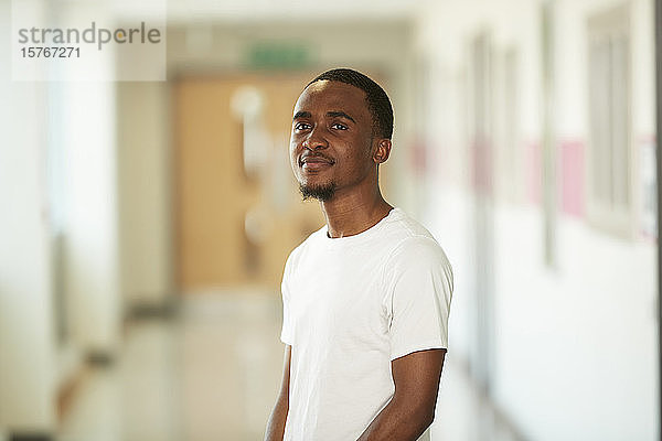 Porträt selbstbewusster junger männlicher Student im Korridor