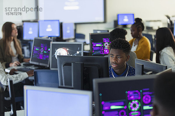 Fokussierter Schüler der Junior High School  der einen Computer in einem dunklen Computerraum benutzt