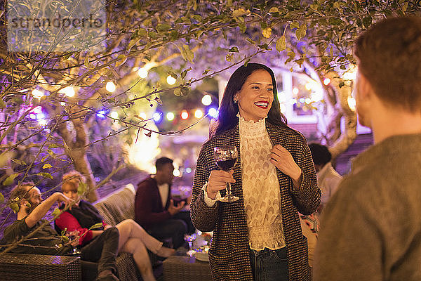 Freunde unterhalten sich und trinken Wein bei einer Gartenparty