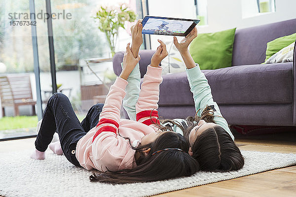 Mädchen nehmen Selfie mit digitalen Tablette auf dem Boden des Wohnzimmers