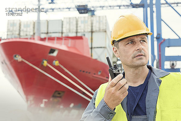 Dockarbeiter mit Walkie-Talkie unter einem Containerschiff auf einer Werft