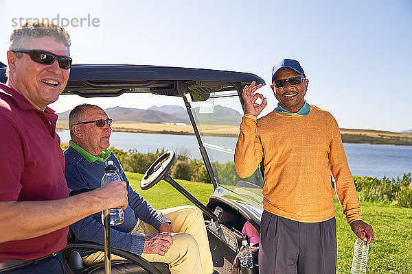 Porträt eines glücklichen  selbstbewussten männlichen Golfspielers  der auf einem sonnigen Golfplatz gestikuliert