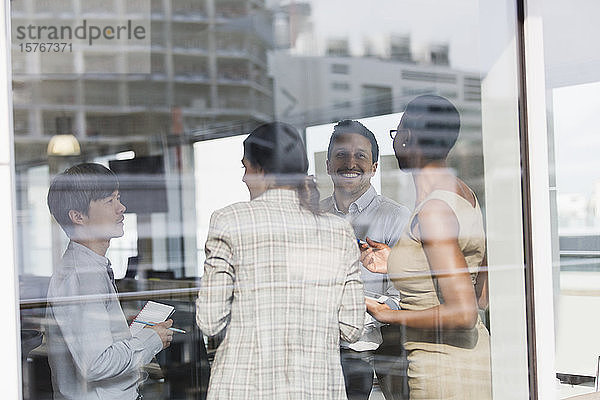 Lächelnde Geschäftsleute im Gespräch am sonnigen Bürofenster