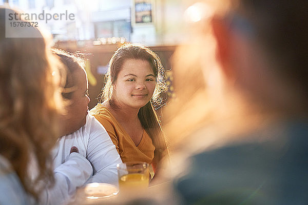 Porträt einer lächelnden jungen Frau mit Down-Syndrom in einem Cafe mit Freunden