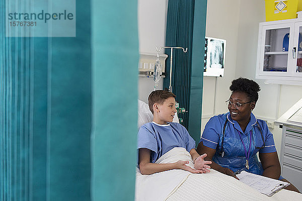 Weibliche Krankenschwester im Gespräch mit einem jungen Patienten im Krankenhauszimmer