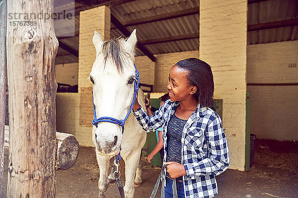 Glückliches Mädchen streichelt Pferd außerhalb der Ställe